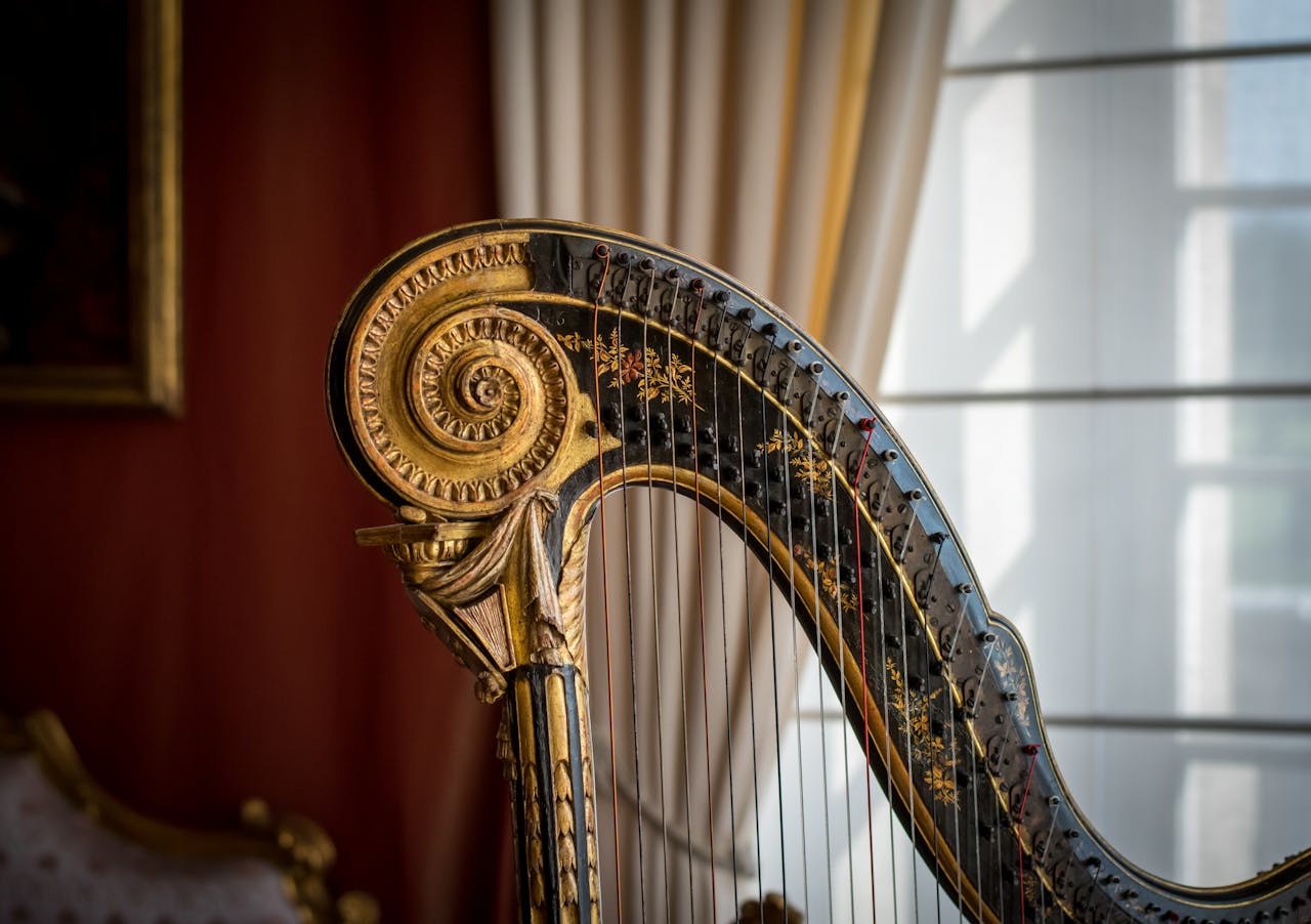 Closeup of an ornate harp with intricate details against a decorative curtain background.